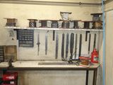 une photo d'un établi dans un garage, avec des outils accrochés au mur