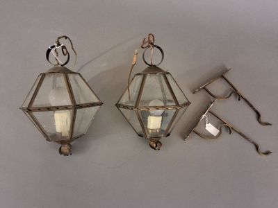 trois lanternes en verre accrochées au mur à côté d'une paire de ciseaux
