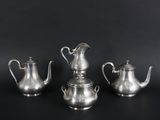 three silver teapots and a coffee pot on a black background