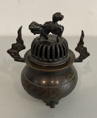 a small bronze pot with a bird on top