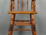 une vieille chaise haute en bois avec une assise en bois posée sur une étagère
