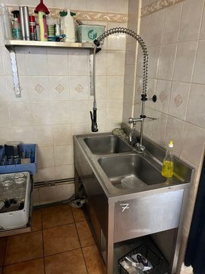 a stainless steel sink in a kitchen with a blue curtain