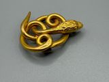 un gros plan d'une broche en or ornée d'un serpent