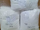Plusieurs sacs contenant des oreillers blancs sont empilés sur une boîte en carton