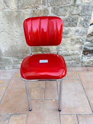 une chaise rouge posée devant un mur de pierre