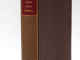 a brown book with a red cover sitting on top of a white surface