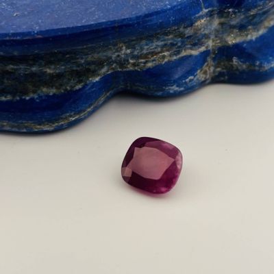 a close up of a pink sapphire stone on a blue rock
