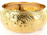 a close up of a gold bowl on a white surface