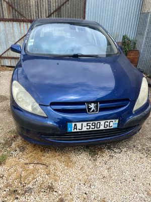 La voiture bleue est garée devant un bâtiment métallique.