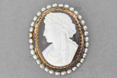 un gros plan sur une broche ornée de perles et représentant le visage d'une femme