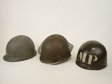 three wwii era helmets are lined up on a white surface