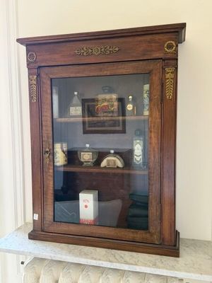 une armoire en bois avec une porte vitrée, posée sur une cheminée