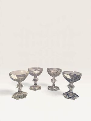 four silver glass goblets and a silver vase on a white surface