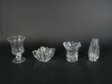 four glass vases are lined up on a black surface