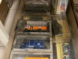 plein de petits camions jouets dans une boîte posée par terre