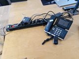 a desk with a phone, laptop, and other electronics on it