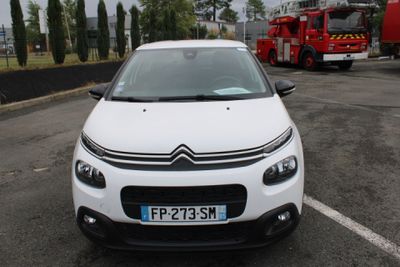 a white car parked in a parking lot with a firetruck in the background