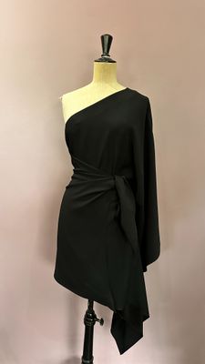 a black dress on a mannequin stand with a white background