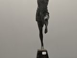 statue en bronze représentant un garçon sur un socle, les bras tendus
