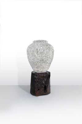 un vase blanc posé sur un socle en bois
