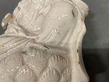 a white statue of a woman sitting on a chair