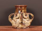 a vase with a face on it sitting on a table