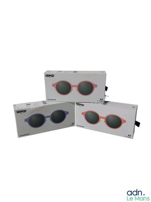 trois paires de lunettes de soleil sont posées dans une boîte sur une surface blanche