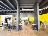 des tables et des chaises dans une pièce aux murs jaunes et au parquet