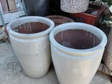two large pots sitting next to each other on the sidewalk