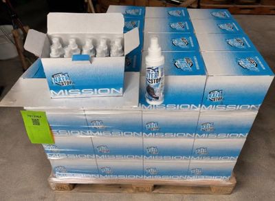 Des cartons d'eau « Mission Mission » sont empilés sur une palette dans un entrepôt