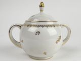 a white teapot with a gold decoration on it