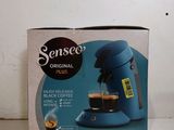 packaging of a blue coffee maker sitting on top of a counter