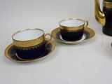 three black and gold coffee cups and saucers on a white table