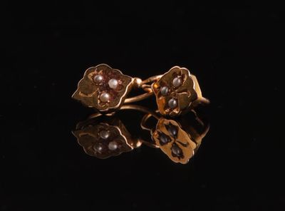 a close up of a pair of gold earrings on a black surface