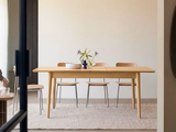 une femme assise à une table sur laquelle se trouve un vase de fleurs