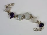 silver bracelet with purple and white stones on it on a white surface