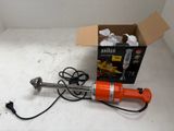 une perceuse électrique orange posée par terre à côté d'une boîte