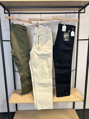 deux paires de pantalons pour homme suspendues à un portant dans un magasin