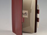 un livre rouge contenant un stylo, avec un bloc-notes posé devant