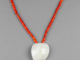 un pendentif blanc en forme de cœur, entouré d'un cordon rouge