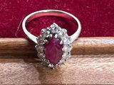 une bague ovale sertie d'un rubis et de diamants, posée sur un fond de velours rouge