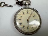 a silver pocket watch with roman numerals on it