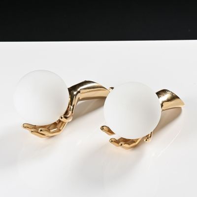 une paire de boutons de manchette en verre blanc et plaqués or, présentés sur un plateau blanc
