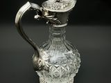 a glass pitcher with a silver handle on a table