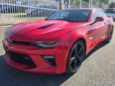 La Chevrolet Camaro rouge est garée devant une clôture blanche.