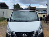 the front of a white van parked in a dirt lot