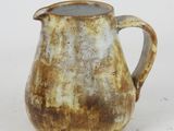 a brown and white pitcher sitting on a white surface