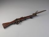 un vieux pistolet avec une poignée en bois sur une surface blanche