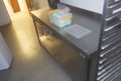 une cuisine équipée d'un plan de travail en inox et d'un micro-ondes
