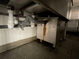 a dirty floor in a kitchen with a sink and pipes